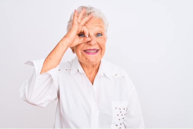 Senior grey-haired woman wearing elegant shirt standing over isolated white background doing ok gesture with hand smiling