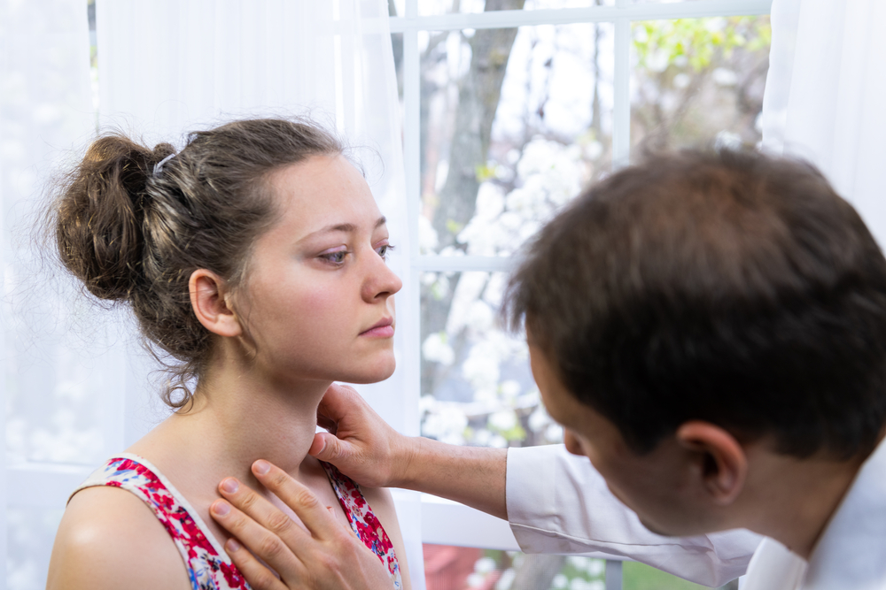 Woman with hyperthyroidism is inspected by a doctor.