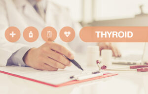Doctor at desk writing on a pad about a patient with a thyroid condition.