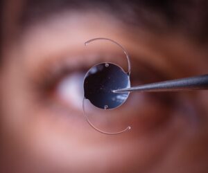 Doctor holds an IOL in front a person's face - this device is meant to last a lifetime