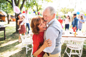Senior couple dances outdoors at a family party with improved vision by IOLs.